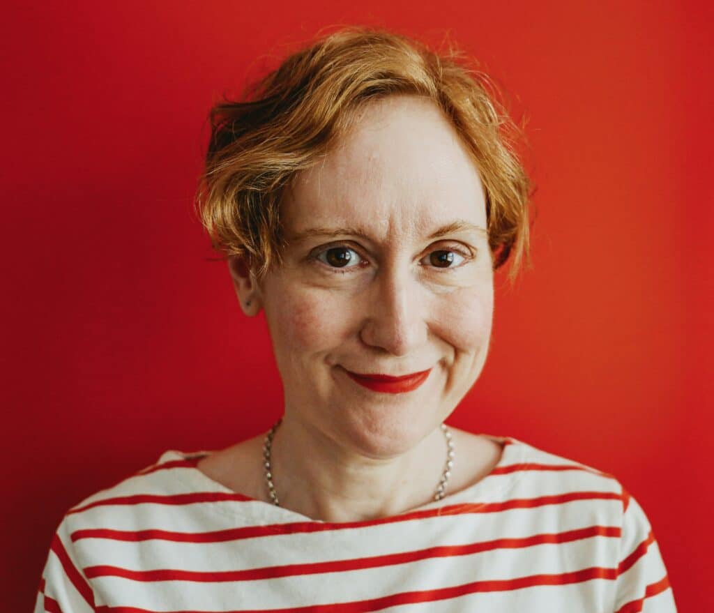 Woman smiling against red background symbolizing ADHD awareness and self-acceptance