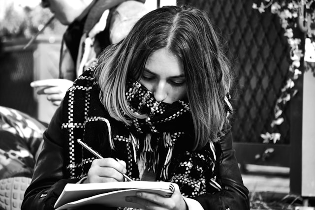 Person writing in a notebook outdoors, emphasizing therapeutic reflection and mindful self-expression.
