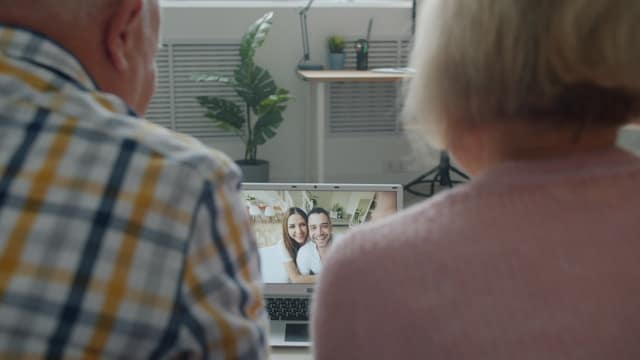 Older couple on video call with family showing secure attachment and maintained connections despite distance
