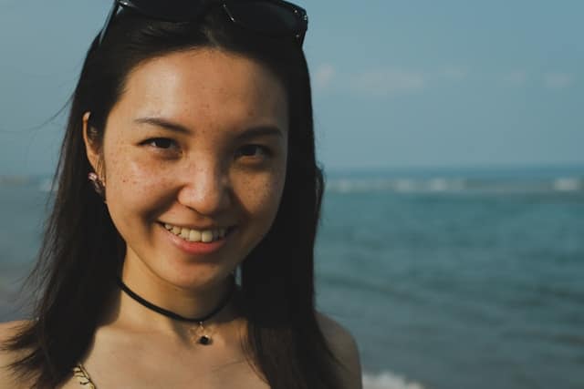 Young woman smiling at beach representing nervous system regulation from mindfulness based therapy in California