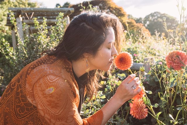 Woman smelling flowers in garden representing present moment awareness in California somatic therapy