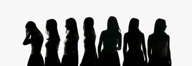 Seven silhouettes of women with long hair standing in a row against white background