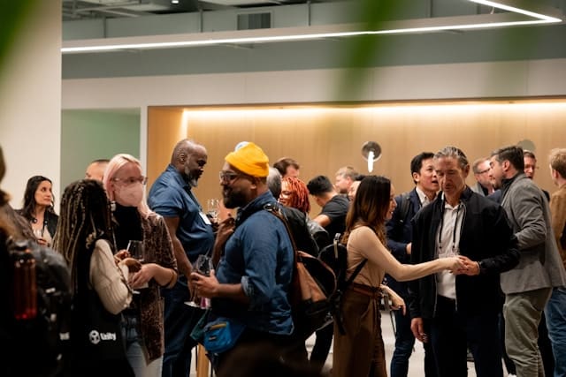 A diverse group of adults of different races and backgrounds mingling and conversing at an indoor gathering, representing the wide range of people and communities served by Center for Mindful Psychotherapy in the San Francisco Bay Area.